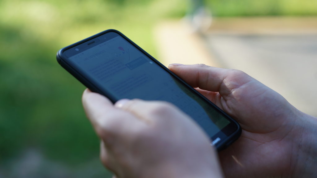 Two hands hold a smartphone with an illegible chat history on the screen.