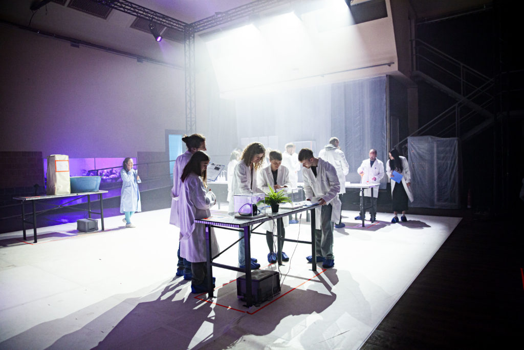 People in white coats at a table, working