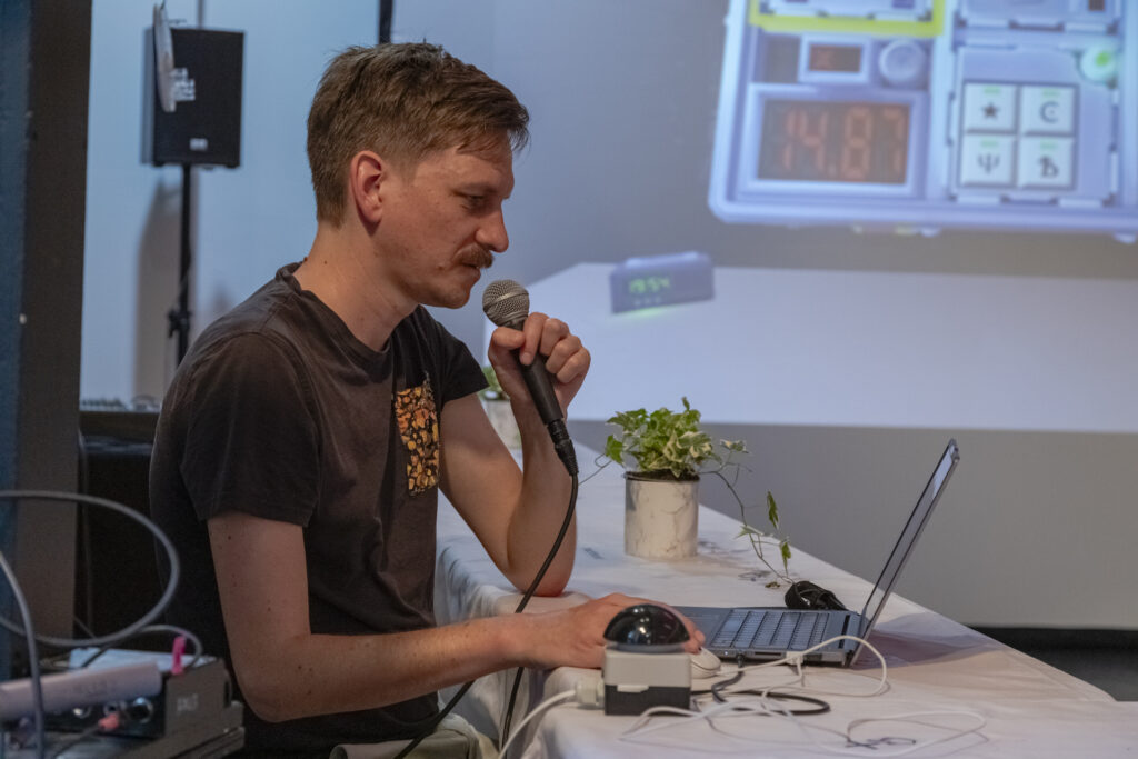 A man is sitting at a table and speaking into a microphone.
