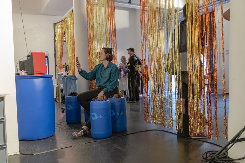 Tinsel curtains at an exhibition, and a visitor watching a documentary.
