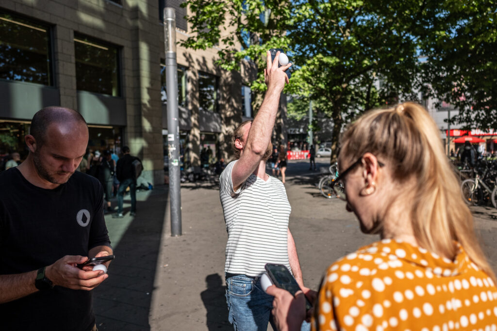 Two people are looking at their smartphones, one is holding his in the air.