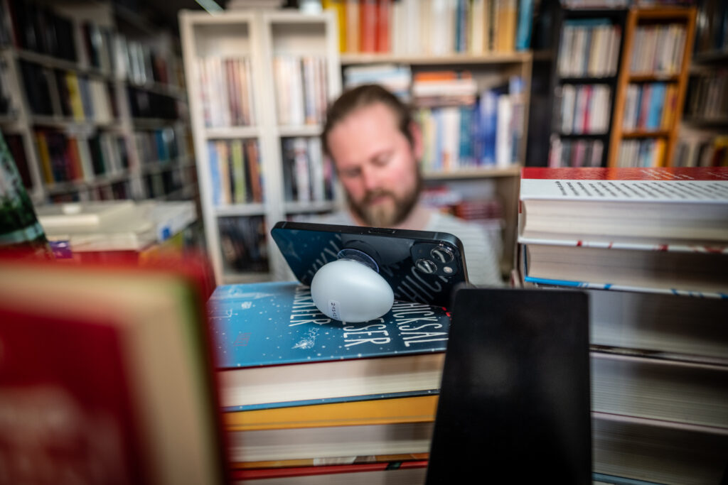 A smartphone lies on a stack of books in a library.