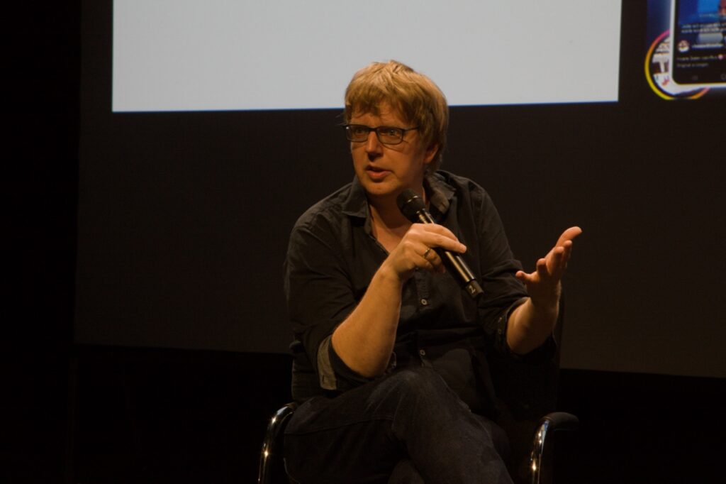 Christian Rakow is sitting and speaking into a microphone.