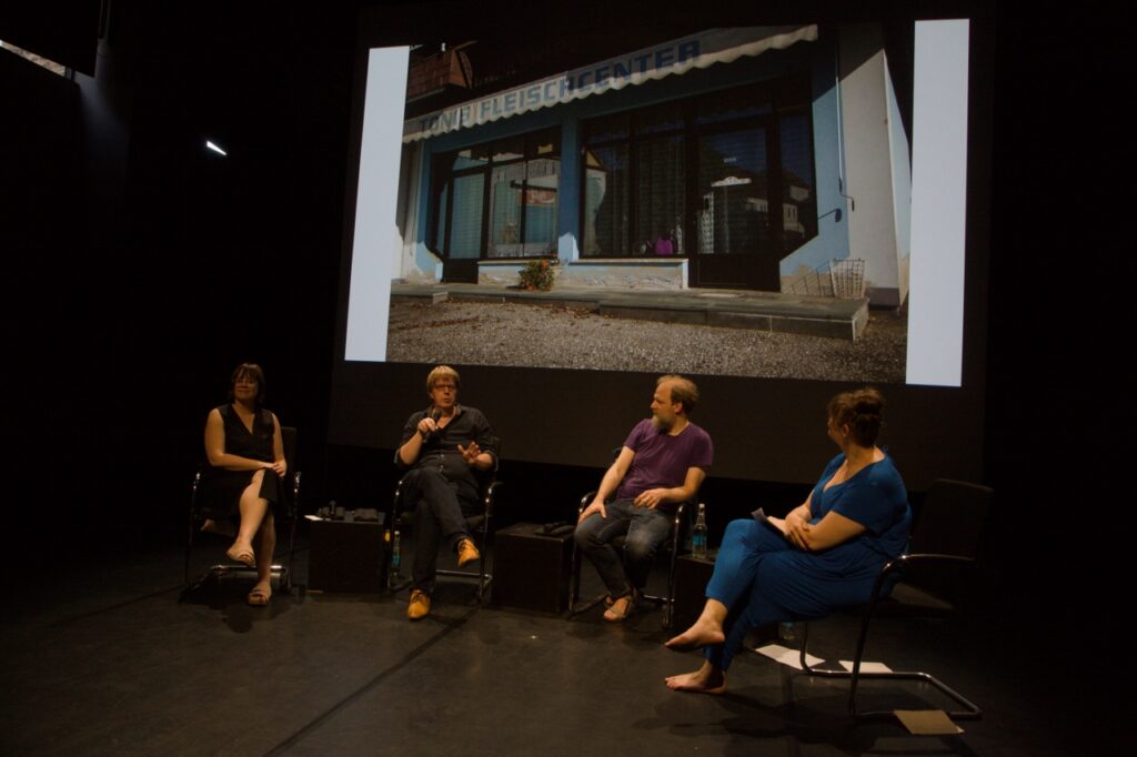 Four people standing in a semicircle on stage.