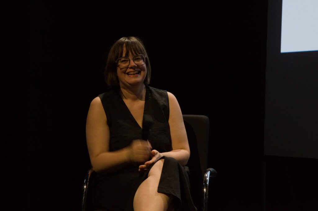 Katja Grawinkel-Claassen is sitting on a chair on stage.