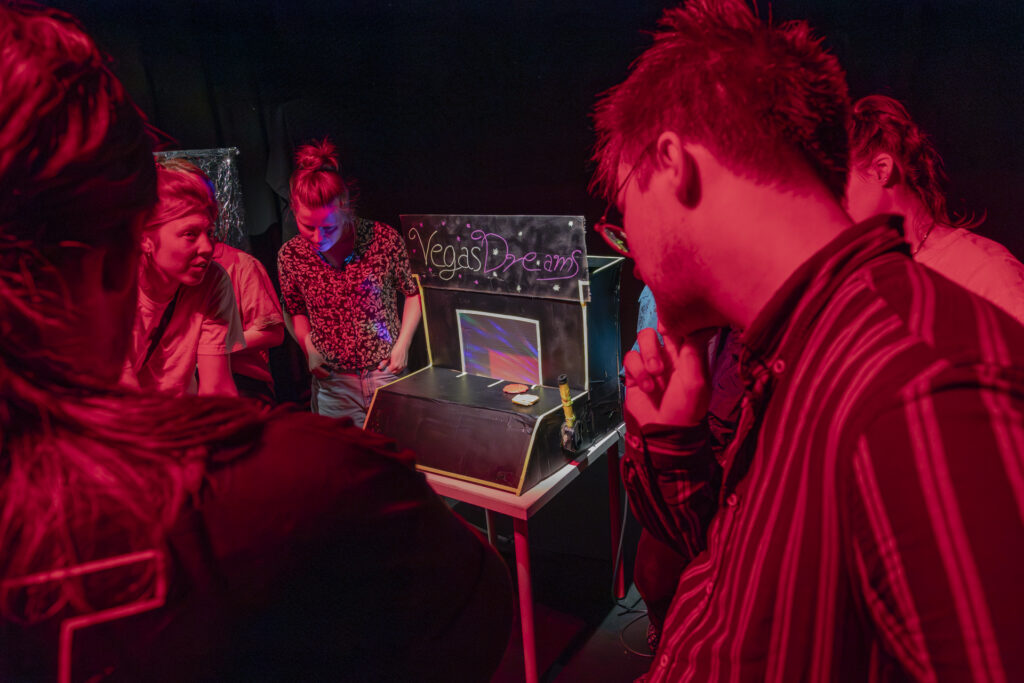 People are standing around a homemade game console.