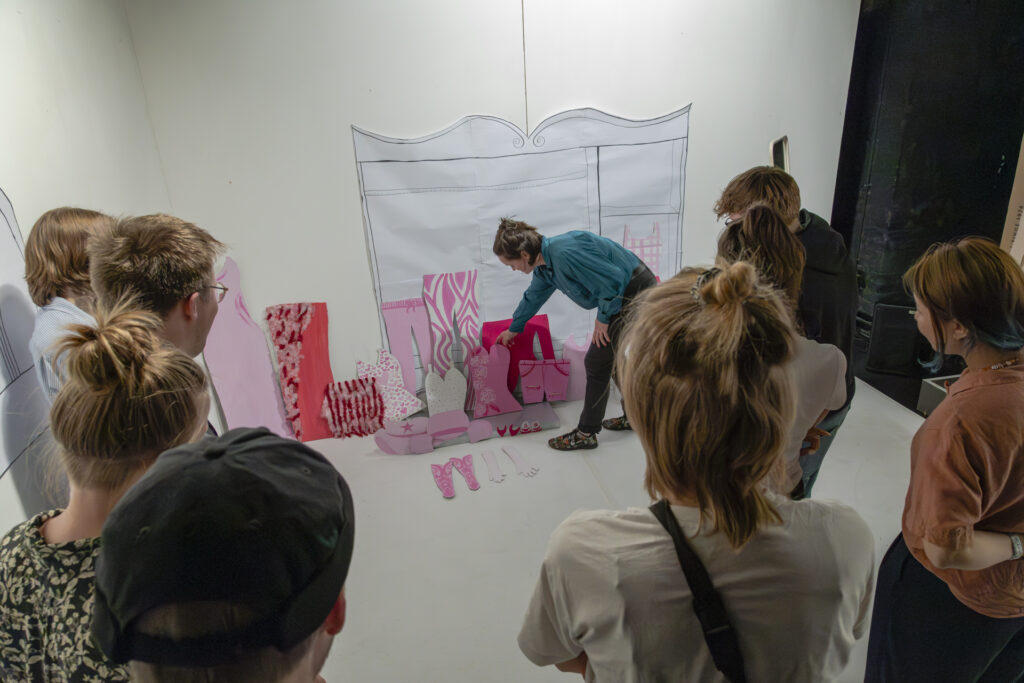 People are browsing through a selection of clothes made out of cardboard.