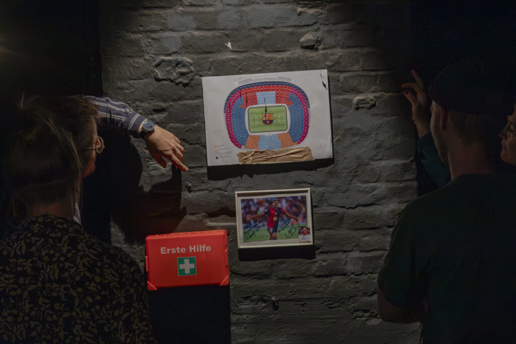 A sketch of a stadium and a photo of a soccer player hang on a black wall.