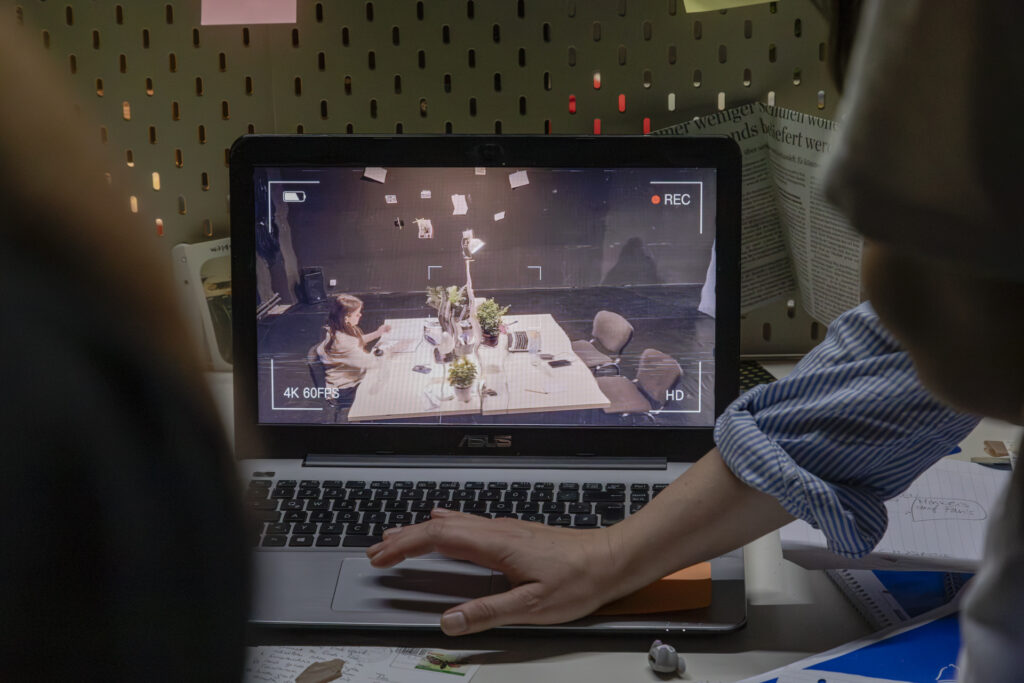 Hands are typing on a laptop with a video playing on the screen.