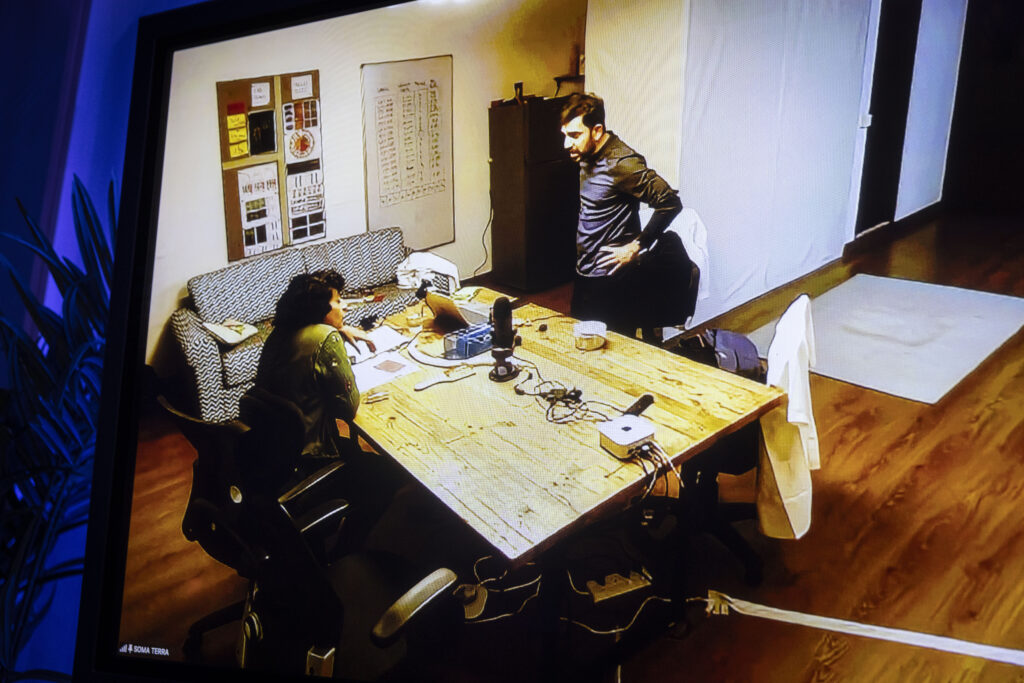 Die Schauspieler:innen Prashant Prakash und Krittika Bhattacharjee im Gespräch an einem Tisch.